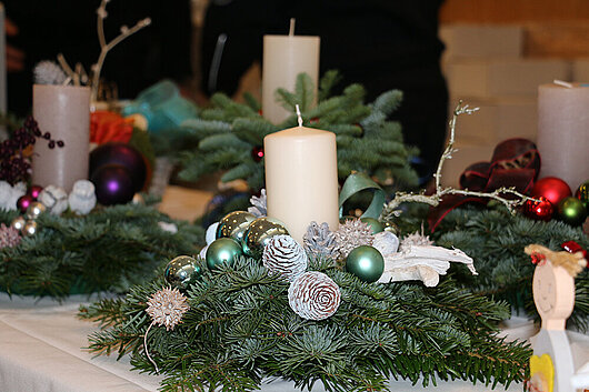 Adventsgesteck mit einer mittigen weißen Kerze und Tannengrün